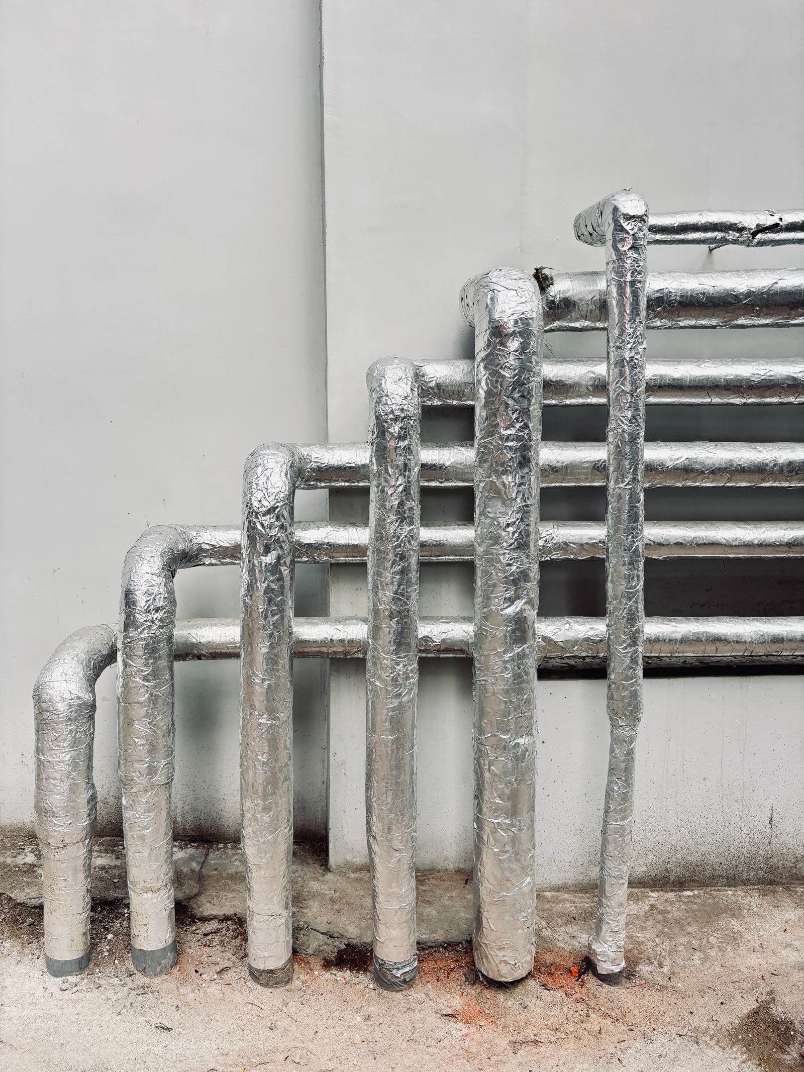 Insulated heating pipes against a wall