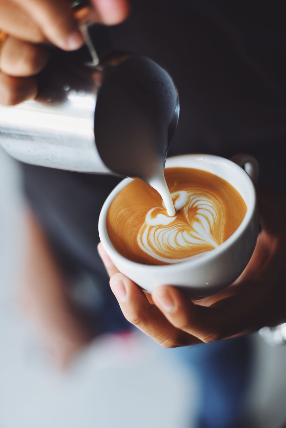 Latte with rosetta art held in two hands