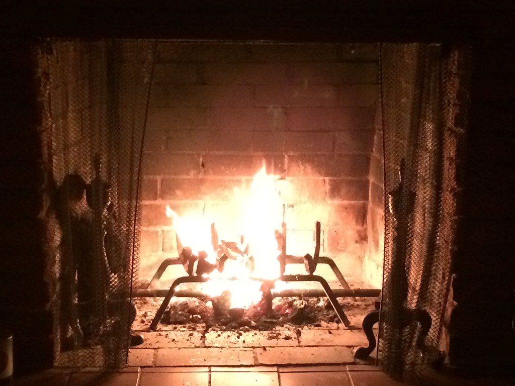 A brick fireplace with a fire and grate