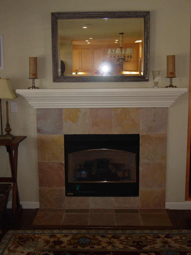 An installed gas fireplace with a stone surround and timber mantel