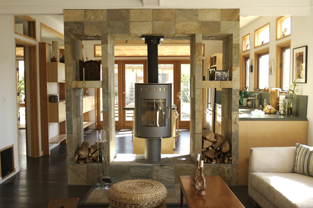 A freestanding gas stove set into a stone surround in an open-plan home