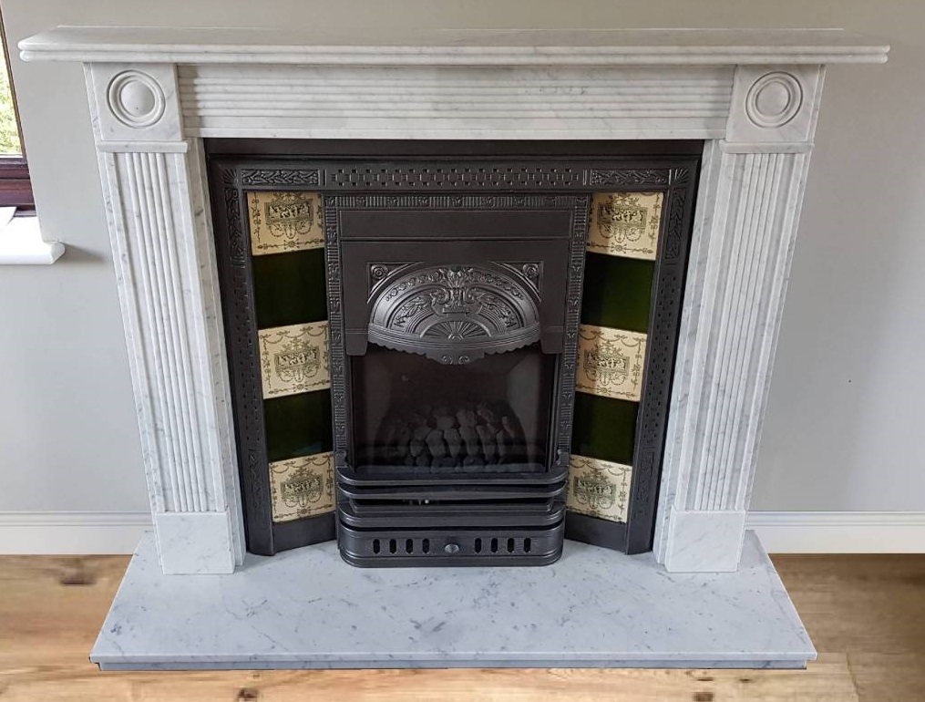 A gas fireplace set into a marble surround with a carved cast-iron insert