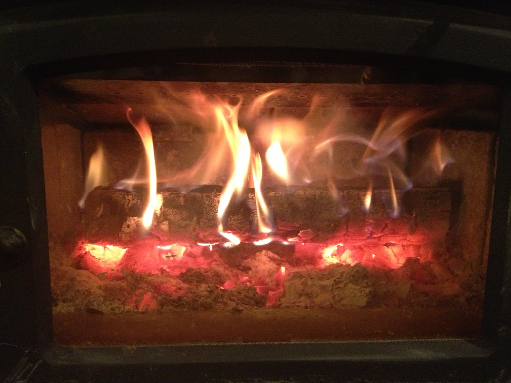 Flames over a log set behind the glass of a gas fireplace