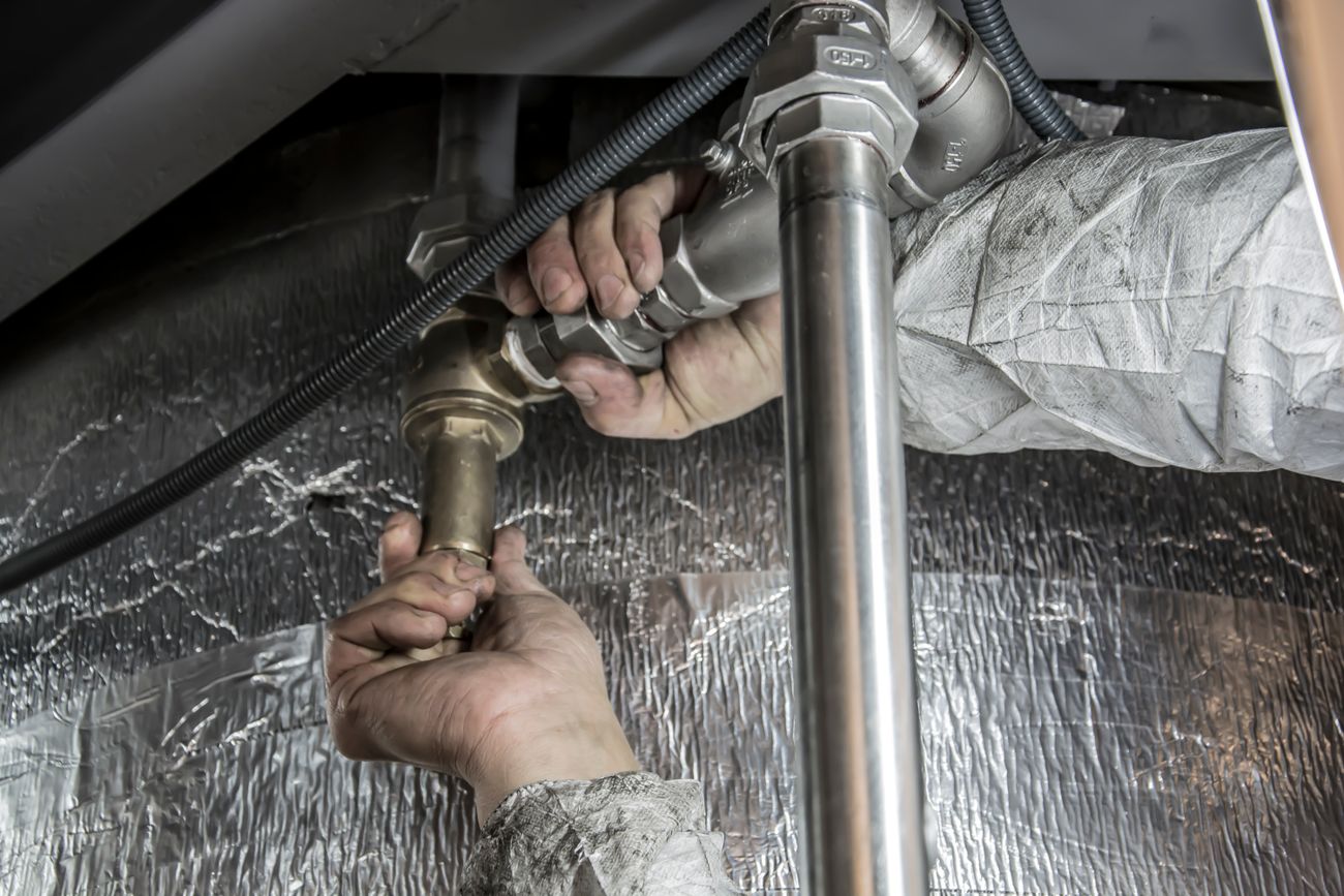 Hands fitting a chrome P-trap under a sink